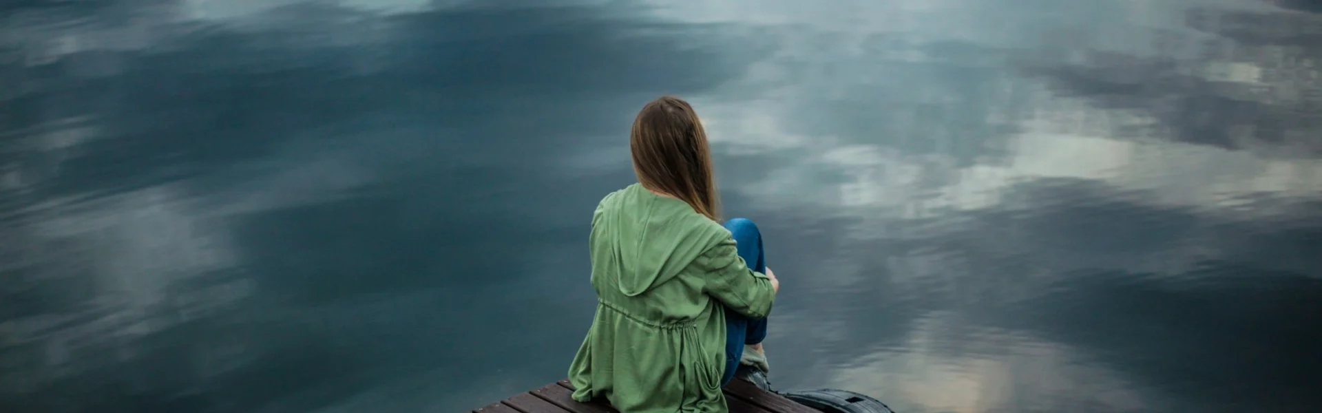 Kvinde med angst sidder og kigger ud mod grå tåge